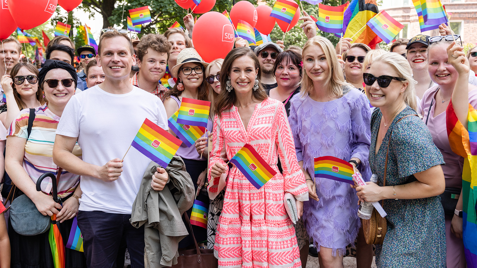 Iloisia SDP:n edustajia Pride tapahtumassa sateenkaarilippujen kanssa, keskellä pääministeri Sanna Marin.
